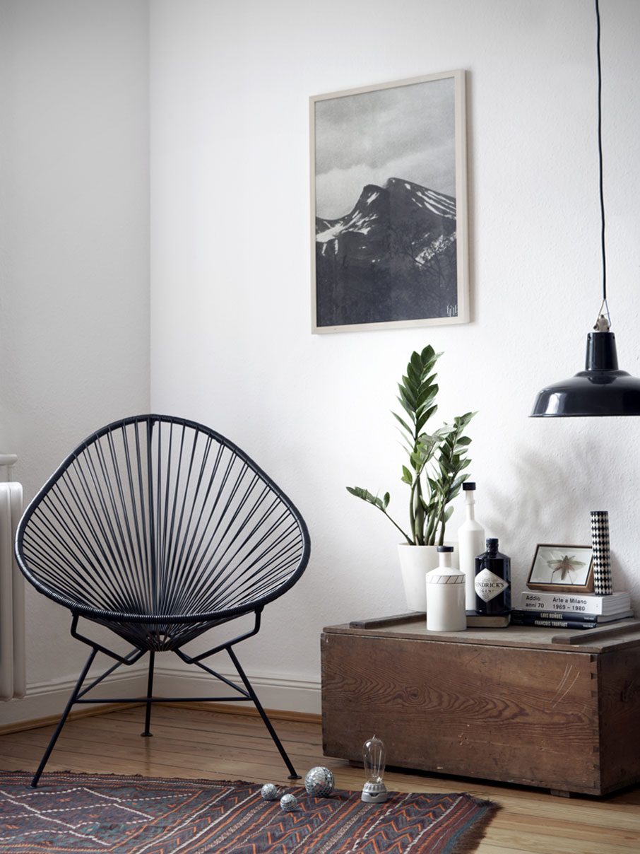 Original Acapulco Chair in der Farbe schwarz neben Holztruhe