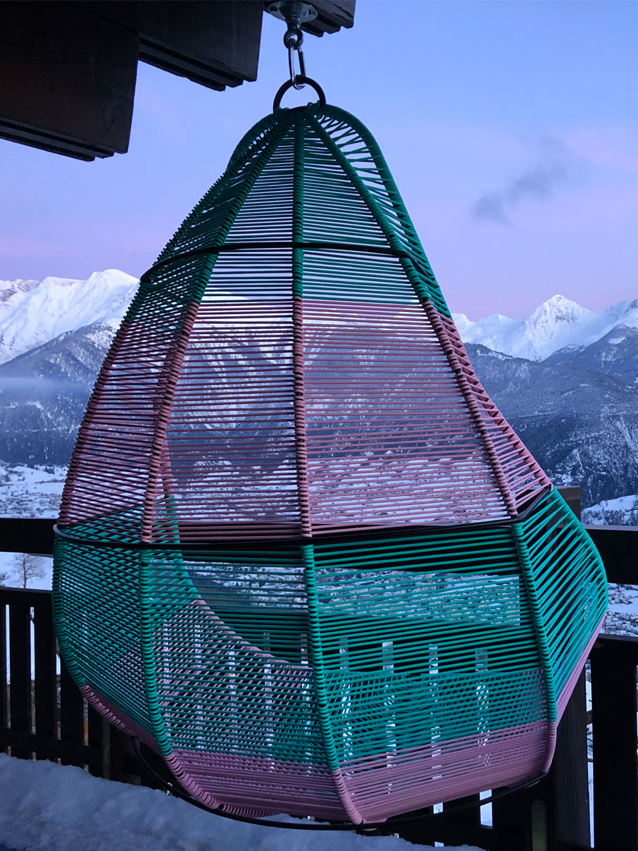 Hängesessel in den Farben türkis-rosa vor Bergpanorama